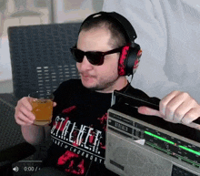 a man wearing headphones and sunglasses is holding a drink and playing a radio