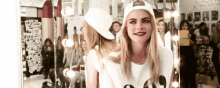 a woman wearing a baseball cap is standing in front of a mirror and smiling