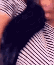 a close up of a person wearing a striped shirt and a black shirt .