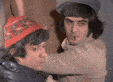 a man wearing a red hat is standing next to another man wearing a blue hat