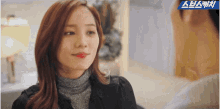 a woman with red lipstick is looking at a man in a room with a blue banner that says ' ae '
