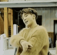 a young man is wearing a yellow sweater and dancing in a room .