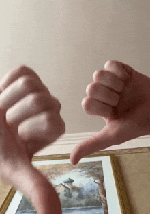 a person giving a thumbs down sign in front of a picture