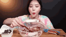 a woman is eating a bowl of cereal with a spoon and a candy bar in the background .