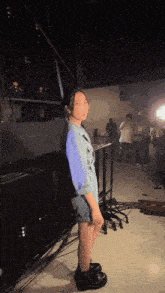 a woman in a denim jacket is standing in a dark room with other people