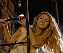a woman in a yellow dress is smiling while holding onto a bar