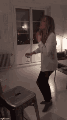 a woman in a white shirt is dancing with a glass in her hand