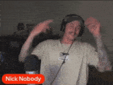 a man wearing headphones and a name tag that says nick nobody is dancing in front of a microphone