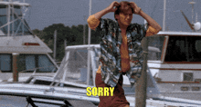 a man in a hawaiian shirt is standing in front of boats and the word sorry is on the screen