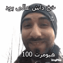 a man with a beard wearing a black hat and smiling with arabic writing on it .