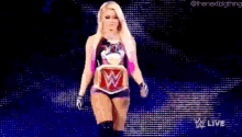 a woman in a wrestling outfit is standing on a stage with a wrestling belt around her waist .
