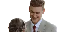 a man in a suit and tie is laughing with a woman in a braid .