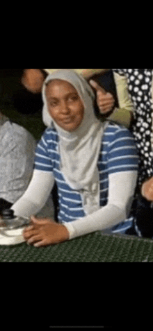 a woman wearing a blue and white striped shirt and a hijab