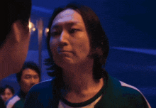 a woman in a green jacket is standing in a dark room with a blurry background .