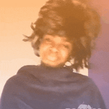 a woman wearing a blue sweater and a wig is smiling
