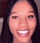 a close up of a woman 's face with braids and a big smile .