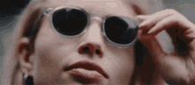 a woman wearing sunglasses is adjusting her sunglasses .