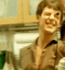 a man in a brown shirt is smiling and looking at the camera .