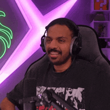 a man wearing headphones sits in front of a microphone and a neon sign that says ' r ' on it