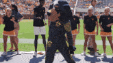a group of people standing around a mascot wearing a t-shirt