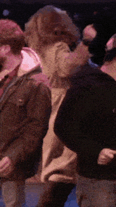 a group of people are standing next to each other on a stage in a dark room .
