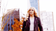a woman in a leather jacket is walking down a street