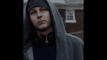 a man wearing headphones and a hooded jacket is giving the middle finger .