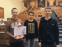 a boy in a gap sweatshirt holds up a certificate