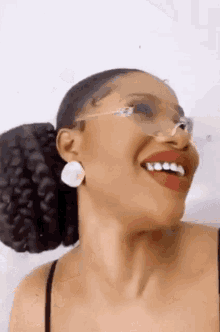 a close up of a woman wearing glasses and red lipstick smiling .