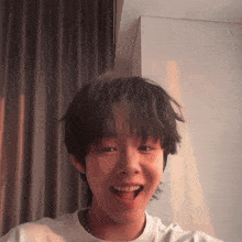 a young boy with a white shirt on is smiling with his mouth open