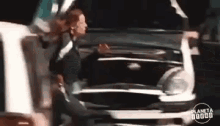 a woman is standing in front of a car with the hood open .