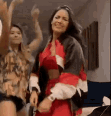 a woman in a red dress is dancing with another woman in a room .