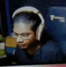 a man wearing headphones and glasses is looking at a computer screen .
