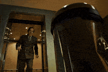 a man in a suit is dancing in an elevator with a sign on the wall that says ' emergency exit '