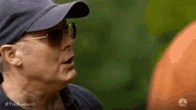 a woman wearing sunglasses and a baseball cap is talking to another woman .