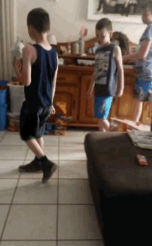 three young boys are playing in a living room and one of them is wearing a shirt that says ' avengers '
