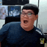 a man wearing glasses and a t-shirt that says stadium on it is making a funny face