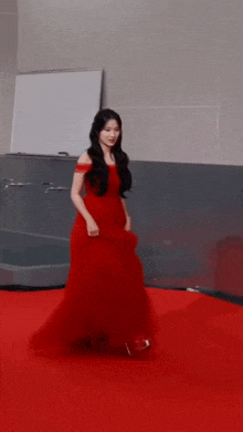 a woman in a long red dress walking on a red carpet