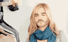 a man with long blonde hair and a beard wearing a blue scarf