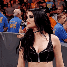 a woman in a black bra is standing in front of a crowd of people wearing event staff shirts .