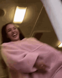 a woman wearing a pink sweater is laughing in a blurry photo