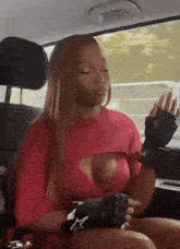 a woman is sitting in the back seat of a car wearing boxing gloves and a red shirt .