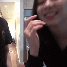 a woman in a black shirt is smiling in front of a fridge