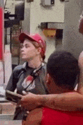 a woman in a red hat is sitting at a counter in a restaurant .