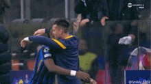 two soccer players hugging in front of a tnt sports 2 advertisement