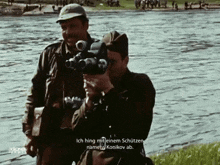 a man is holding a camera in front of a river and says ich hing mit einem schutzen nameb konkov ab