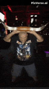 a man wearing a shirt that says iron maiden holds a large horn over his head