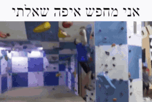 a man is climbing a wall in a room with hebrew writing on it