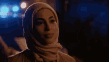 a woman wearing a hijab looks at the camera in a blurry photo
