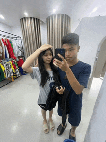 a man and a woman are taking a picture of themselves in a dressing room with a sign on the wall that says exit